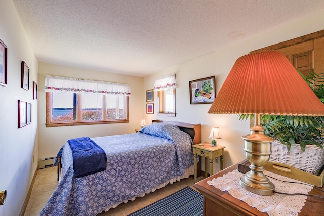 bedroom with tile patterned floors, baseboards, baseboard heating, and a textured ceiling