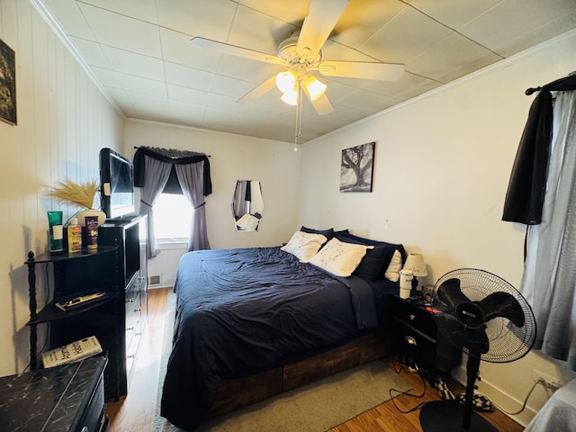 bedroom with ceiling fan, visible vents, wood finished floors, and ornamental molding