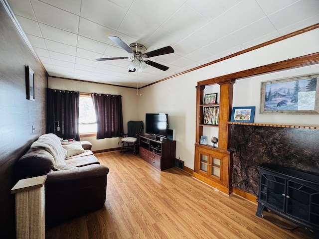 living room featuring a ceiling fan, crown molding, wood finished floors, and baseboards