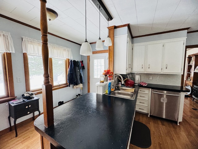 kitchen featuring dark countertops, a sink, crown molding, and stainless steel dishwasher