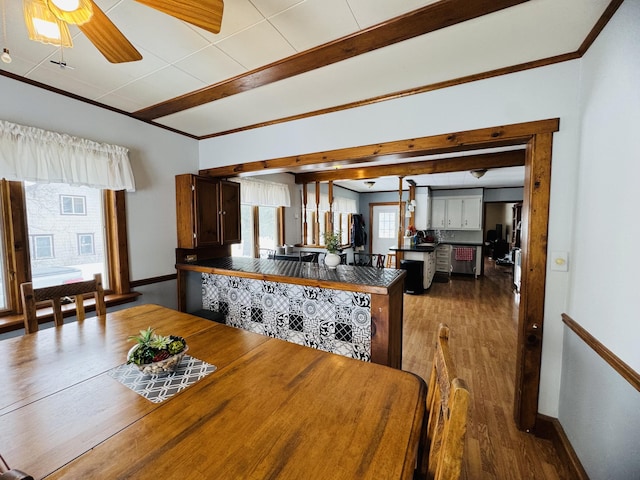 dining space with beamed ceiling, wood finished floors, baseboards, and ornamental molding