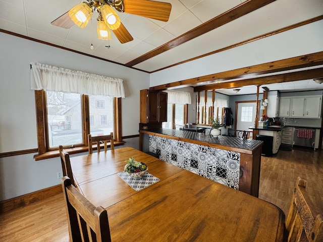 dining room with baseboards, wood finished floors, a ceiling fan, and ornamental molding