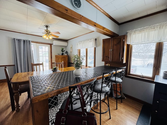 kitchen with a wealth of natural light, light wood-type flooring, crown molding, and a wall unit AC