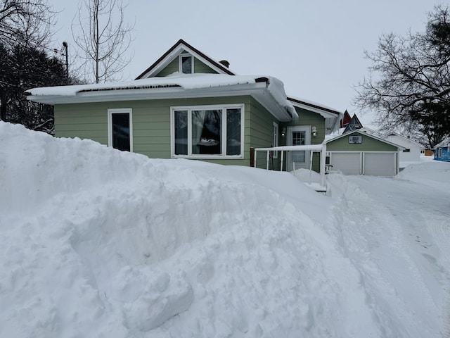 snow covered rear of property with a garage