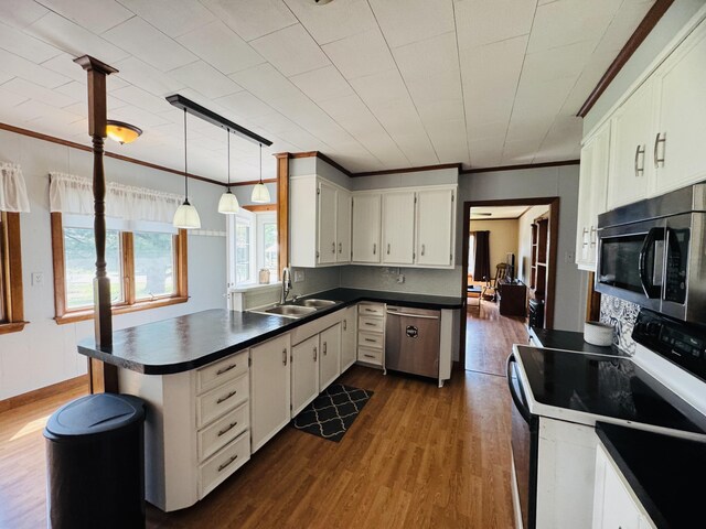 30 Washington St, Caribou, ME 04736 - kitchen featuring stainless steel appliances, a sink, a peninsula, dark countertops, and dark wood-type flooring