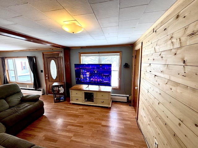 living area featuring light wood-type flooring, wooden walls, a baseboard heating unit, and ornamental molding