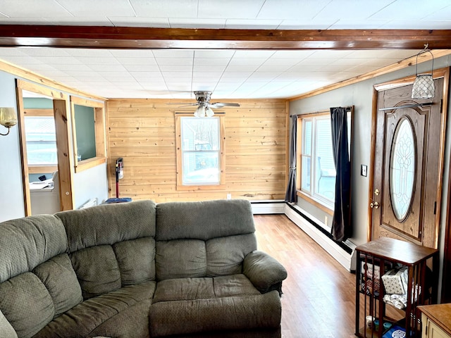 living room featuring light wood finished floors, a baseboard radiator, baseboard heating, a ceiling fan, and wooden walls