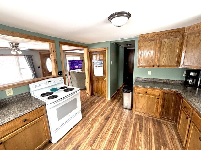 kitchen featuring light wood finished floors, electric range, dark countertops, and brown cabinets