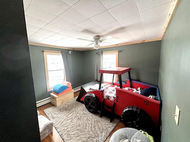 bedroom with a ceiling fan, a baseboard radiator, ornamental molding, and wood finished floors