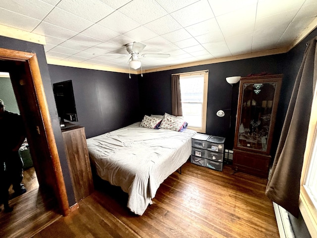 bedroom featuring ceiling fan, baseboard heating, and wood finished floors