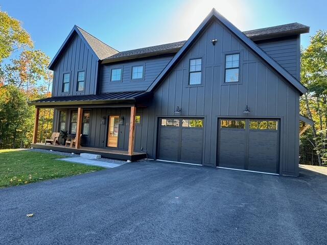 view of front of property with a standing seam roof, covered porch, a garage, driveway, and board and batten siding