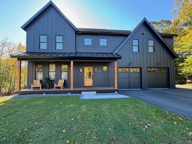 65 Sky Dr, Windham, ME 04062 - rear view of house with driveway, an attached garage, a standing seam roof, covered porch, and board and batten siding
