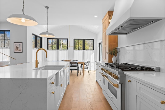 kitchen featuring lofted ceiling, a sink, light wood-type flooring, double oven range, and custom range hood