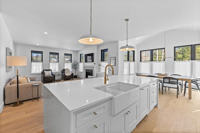 65 Sky Dr, Windham, ME 04062 - kitchen with pendant lighting, a fireplace, light wood-style floors, white cabinetry, and a sink