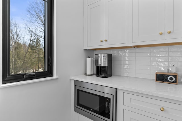 65 Sky Dr, Windham, ME 04062 - kitchen featuring light stone counters, tasteful backsplash, stainless steel microwave, and white cabinetry