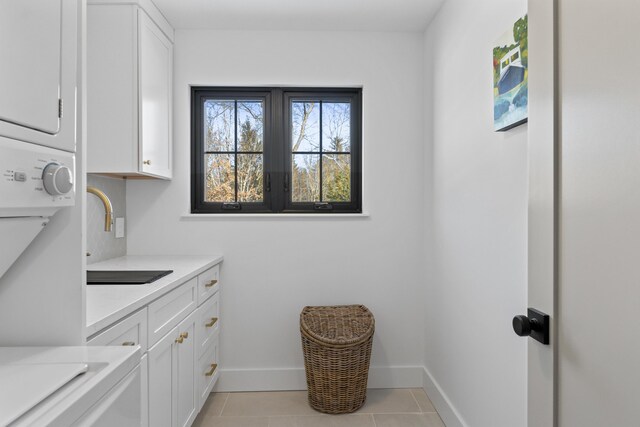 65 Sky Dr, Windham, ME 04062 - laundry room with light tile patterned flooring, a sink, baseboards, stacked washing maching and dryer, and cabinet space