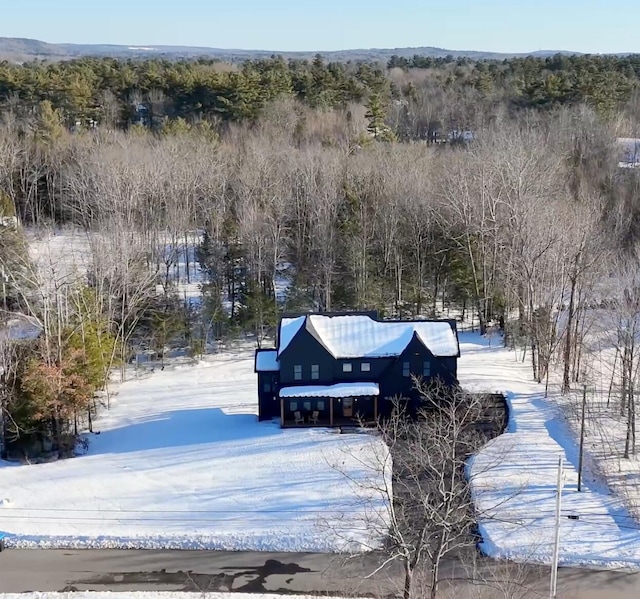 snowy aerial view featuring a wooded view