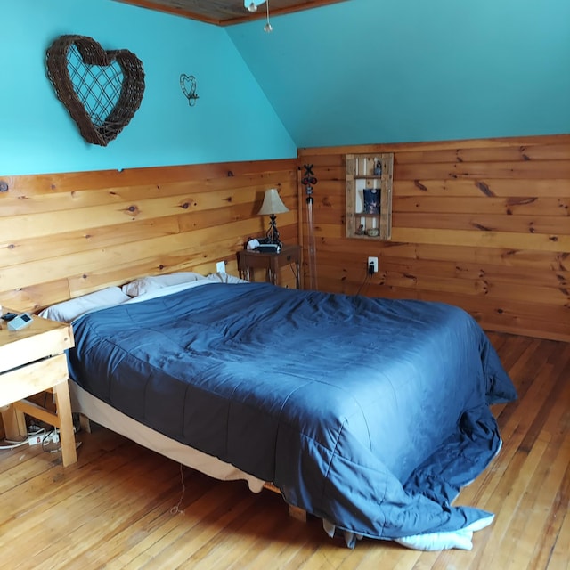 bedroom with wood-type flooring, lofted ceiling, and wood walls