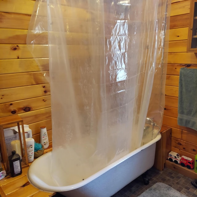 bathroom with wooden walls and shower / bathtub combination with curtain