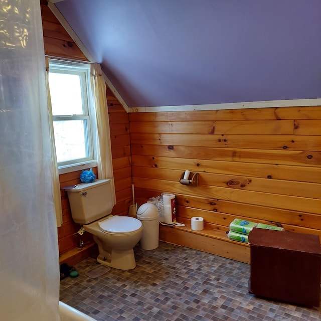 bathroom featuring wood walls, toilet, and lofted ceiling