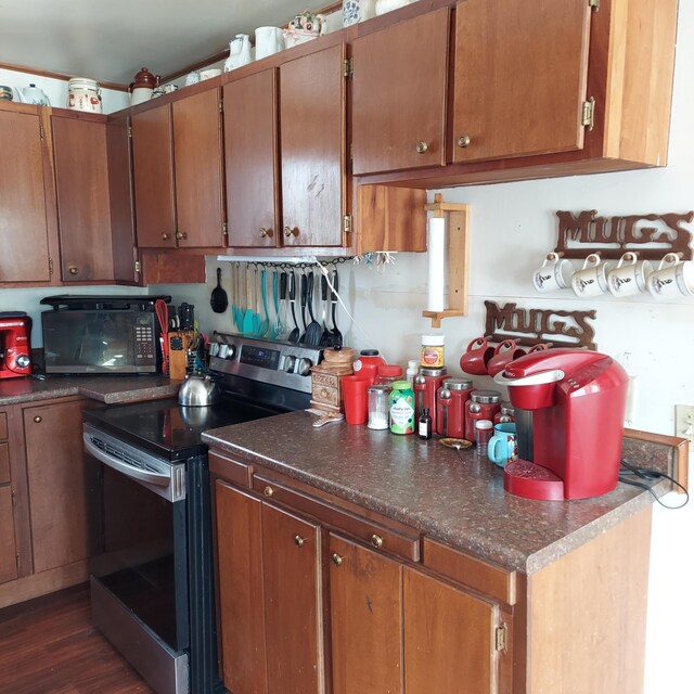 kitchen featuring stainless steel electric range oven, dark wood-style floors, brown cabinetry, and black microwave