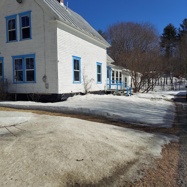 view of side of property featuring a standing seam roof, a chimney, and metal roof