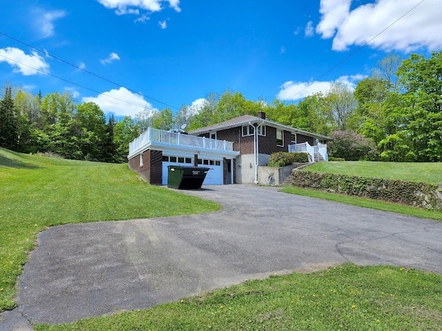 view of front of property featuring driveway, a front lawn, an attached garage, and brick siding