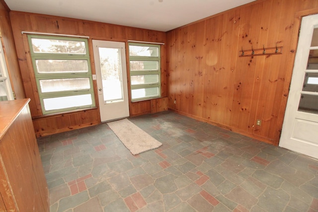 interior space with stone finish floor, wood walls, and stairway