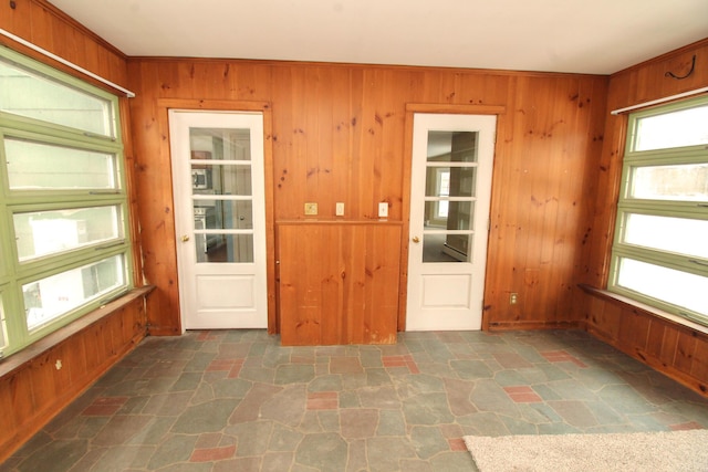 empty room featuring wood walls and stone flooring