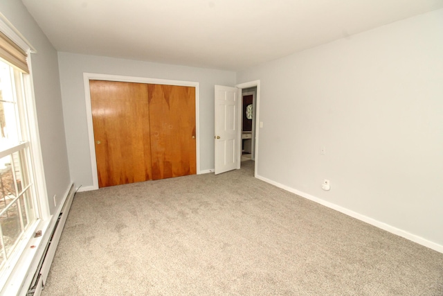 unfurnished bedroom with carpet floors, a closet, baseboards, and baseboard heating