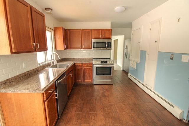 kitchen with a baseboard radiator, dark wood-style flooring, a sink, stainless steel appliances, and backsplash