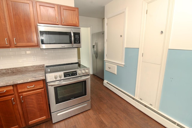 kitchen with stainless steel appliances, dark wood-style flooring, baseboard heating, backsplash, and brown cabinetry