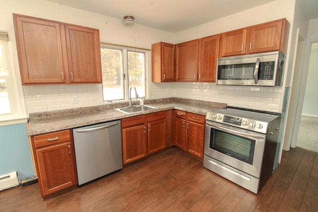 kitchen featuring dark wood-style flooring, backsplash, appliances with stainless steel finishes, a baseboard heating unit, and a sink