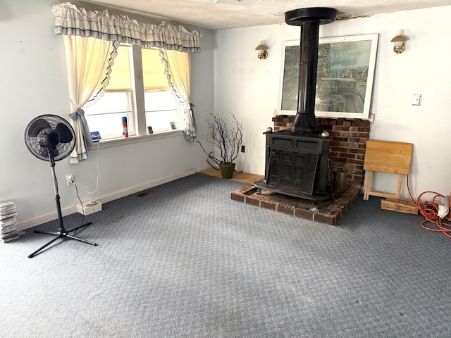 interior space with a wood stove, carpet flooring, baseboards, and visible vents