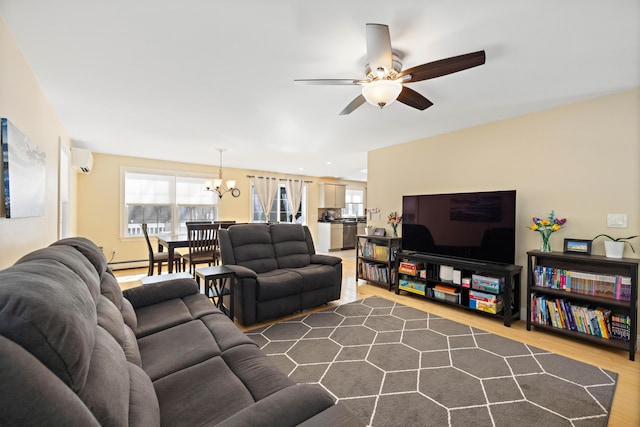 living room with a baseboard heating unit, an AC wall unit, wood finished floors, and ceiling fan with notable chandelier