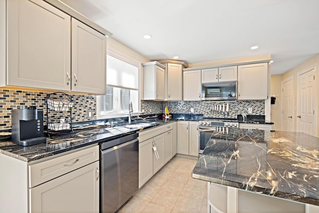 kitchen featuring a sink, dark stone counters, light tile patterned floors, and stainless steel appliances