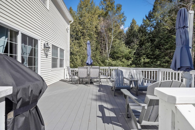 wooden terrace featuring area for grilling and outdoor dining area