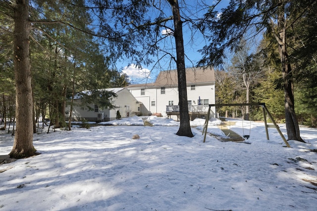 snow covered back of property with a wooden deck