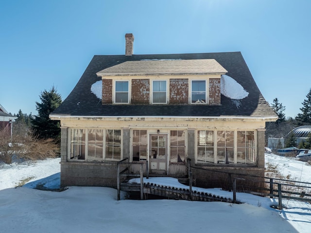 view of front of home featuring a chimney, fence, and a sunroom