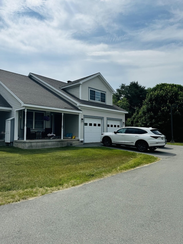 traditional home featuring an attached garage, covered porch, driveway, and a front lawn