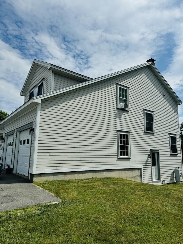 view of property exterior with a garage, aphalt driveway, and a lawn