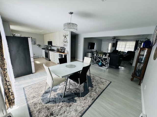 dining space with a baseboard radiator, baseboards, light wood-style flooring, and a ceiling fan