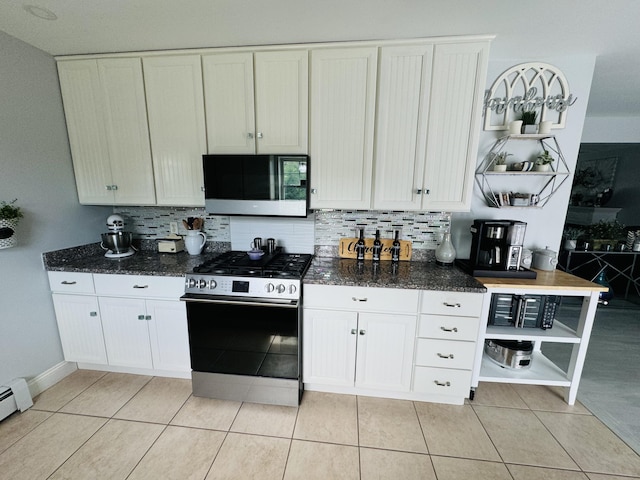 kitchen featuring dark stone counters, stainless steel gas range oven, light tile patterned flooring, and tasteful backsplash