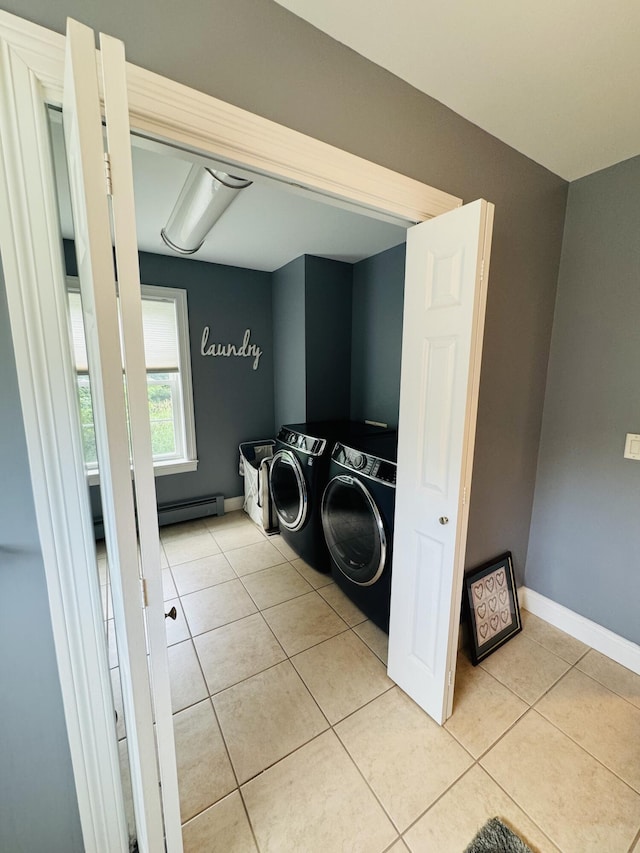 clothes washing area featuring light tile patterned flooring, a baseboard radiator, laundry area, baseboards, and washing machine and clothes dryer