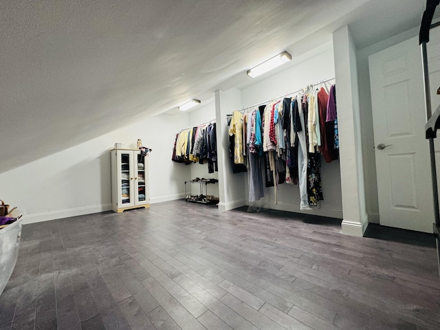 spacious closet with lofted ceiling and dark wood-style flooring