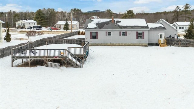 snow covered house with a fenced backyard