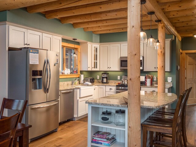 kitchen with light stone counters, stainless steel appliances, light wood-type flooring, beamed ceiling, and glass insert cabinets