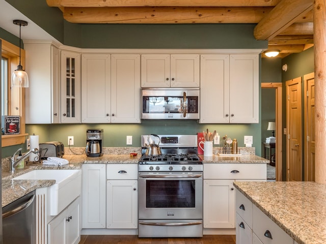 kitchen with hanging light fixtures, appliances with stainless steel finishes, white cabinets, and glass insert cabinets