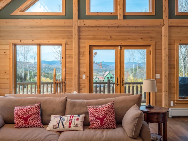 living room featuring a baseboard heating unit, wood finished floors, a mountain view, and wooden walls