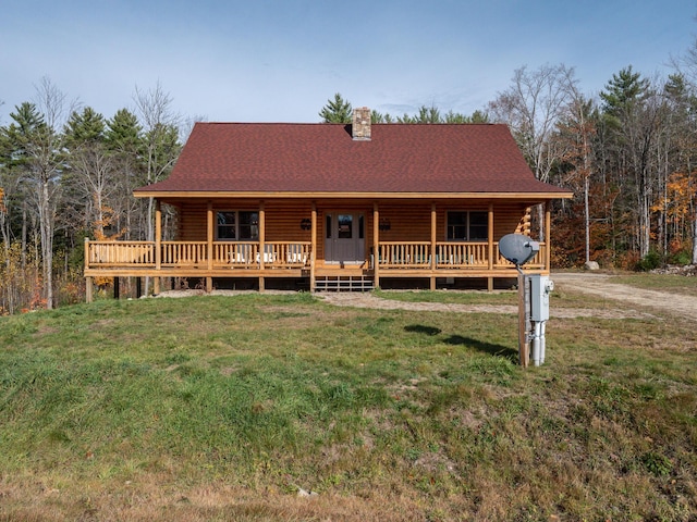 log cabin featuring a chimney, a shingled roof, covered porch, log exterior, and a front lawn